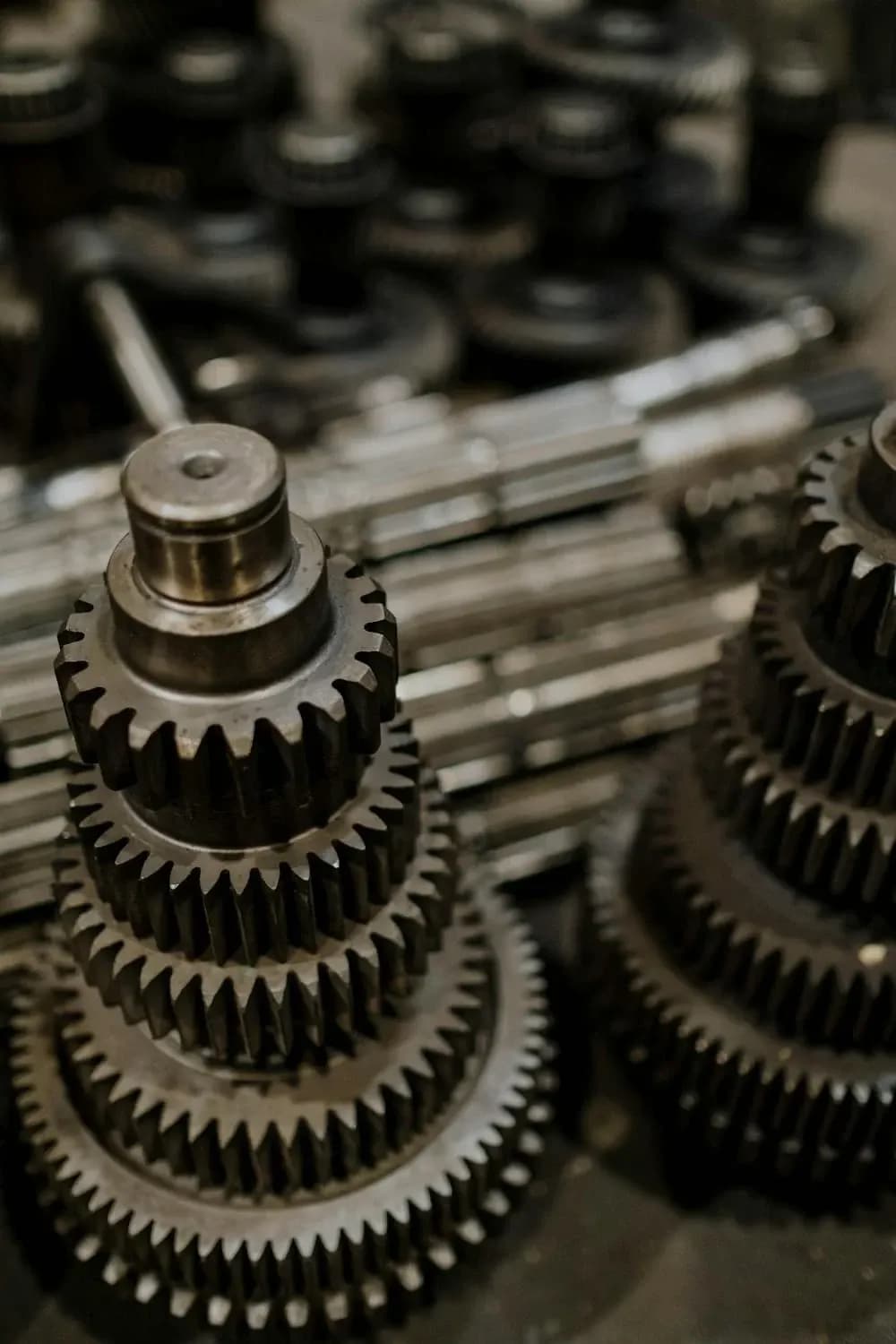 Stapel gebrauchter Getriebe in einer Werkstatt, sortiert und bereit für den Wiederverkauf, einschließlich Schalt- und Automatikgetriebe für verschiedene Fahrzeugtypen.