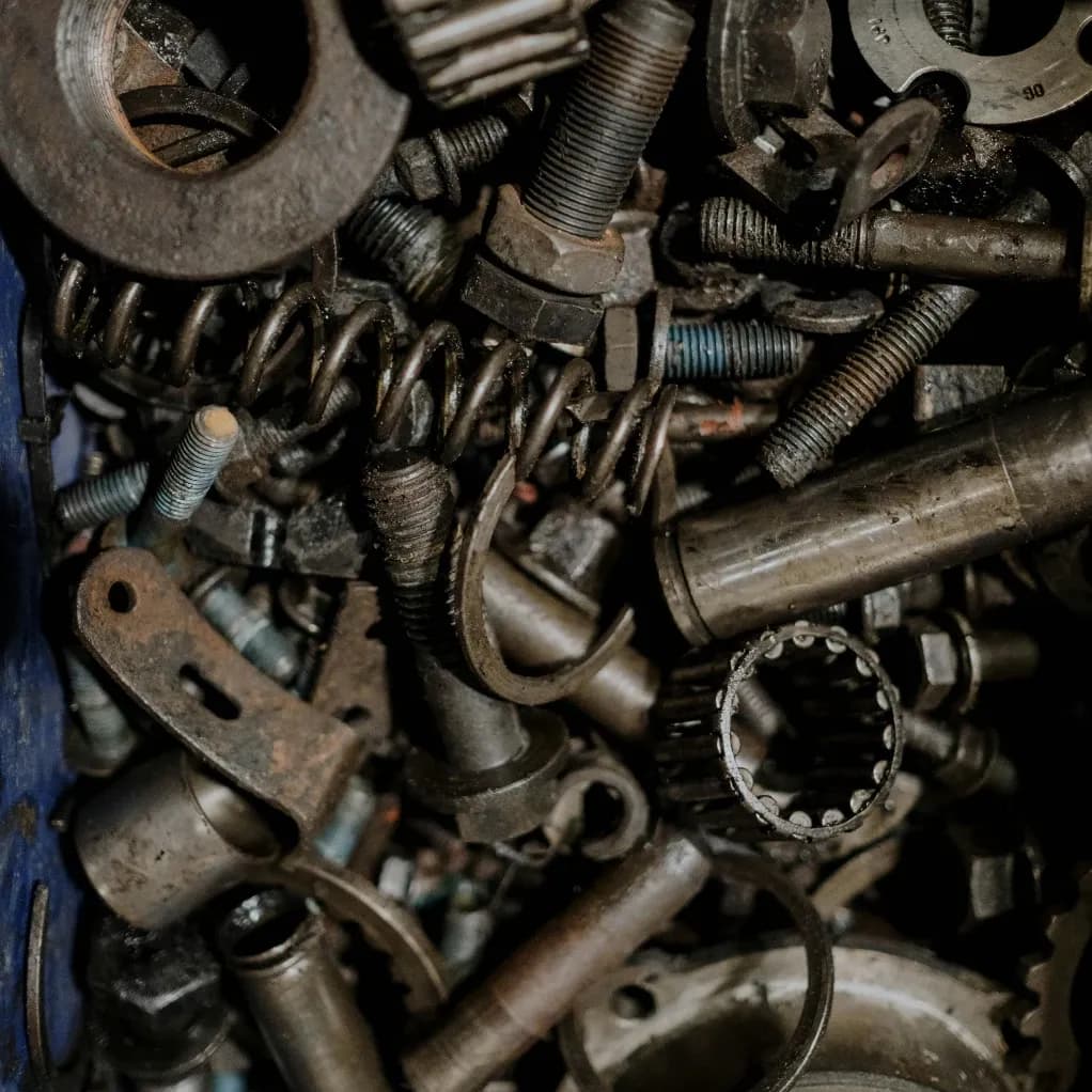 Stapel gebrauchter Autoteile in einer Werkstatt, darunter Motoren, Getriebe und Karosserieteile, sorgfältig sortiert zur Wiederverwendung.